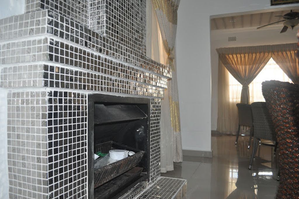 A modern interior with a tiled fireplace, a dining area with a chair, and a ceiling fan.