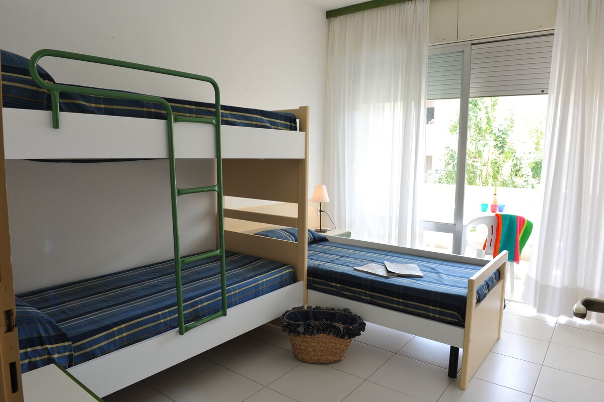 A bunk bed room with a window, a lamp, and a basket on the floor.