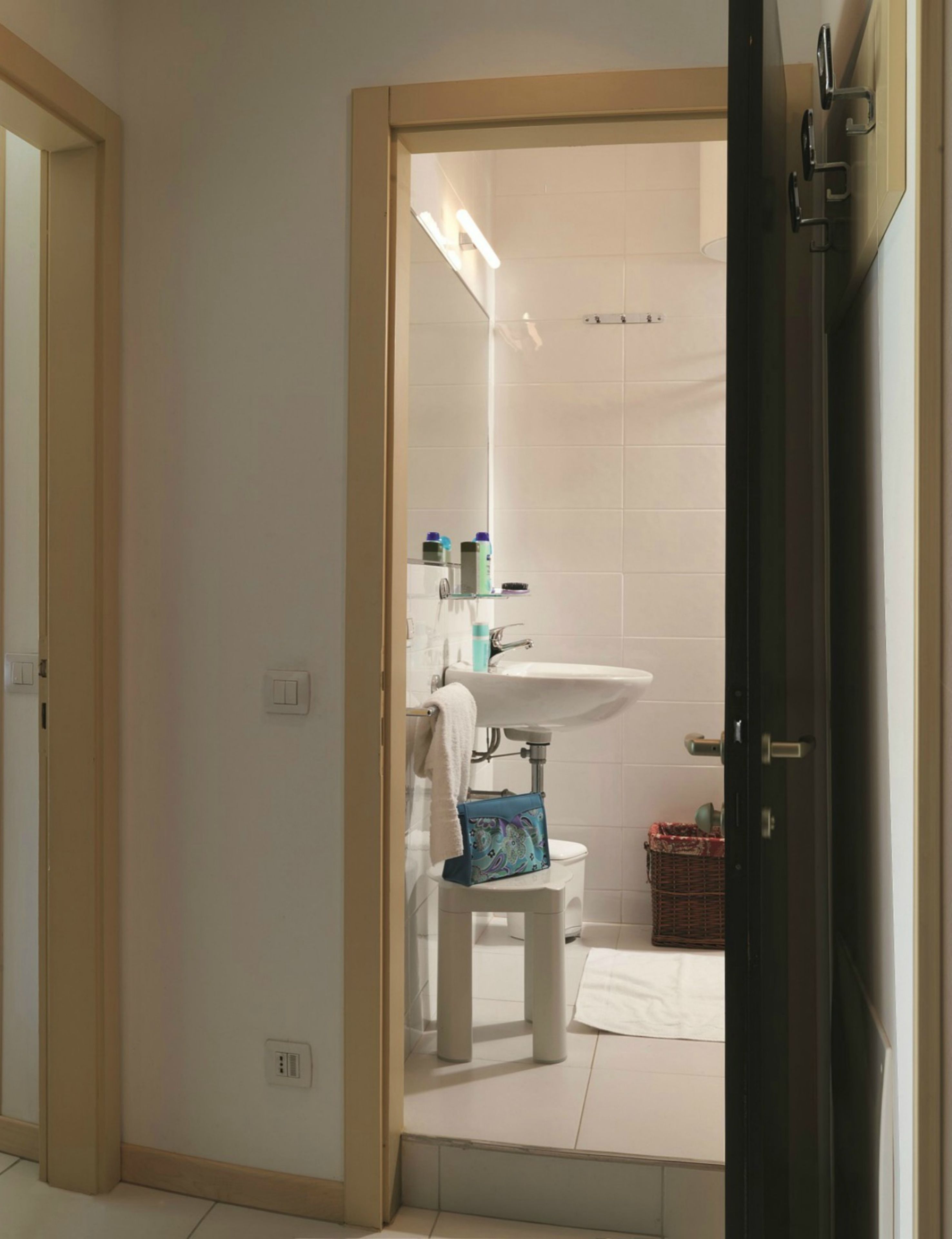 A bathroom with a white sink, toilet, and a small stool with a towel.