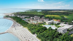 Vista aerea di una località balneare con spiaggia, piscina e diversi edifici alberghieri.