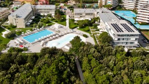 Una vista aerea di un complesso alberghiero con diversi edifici, una piscina centrale e vegetazione circostante.