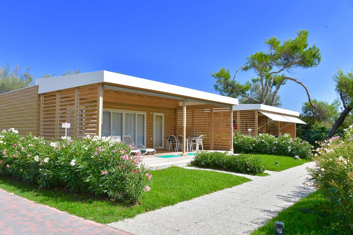 A modern, two-story house with a covered patio, a swimming pool, and a well-maintained garden.