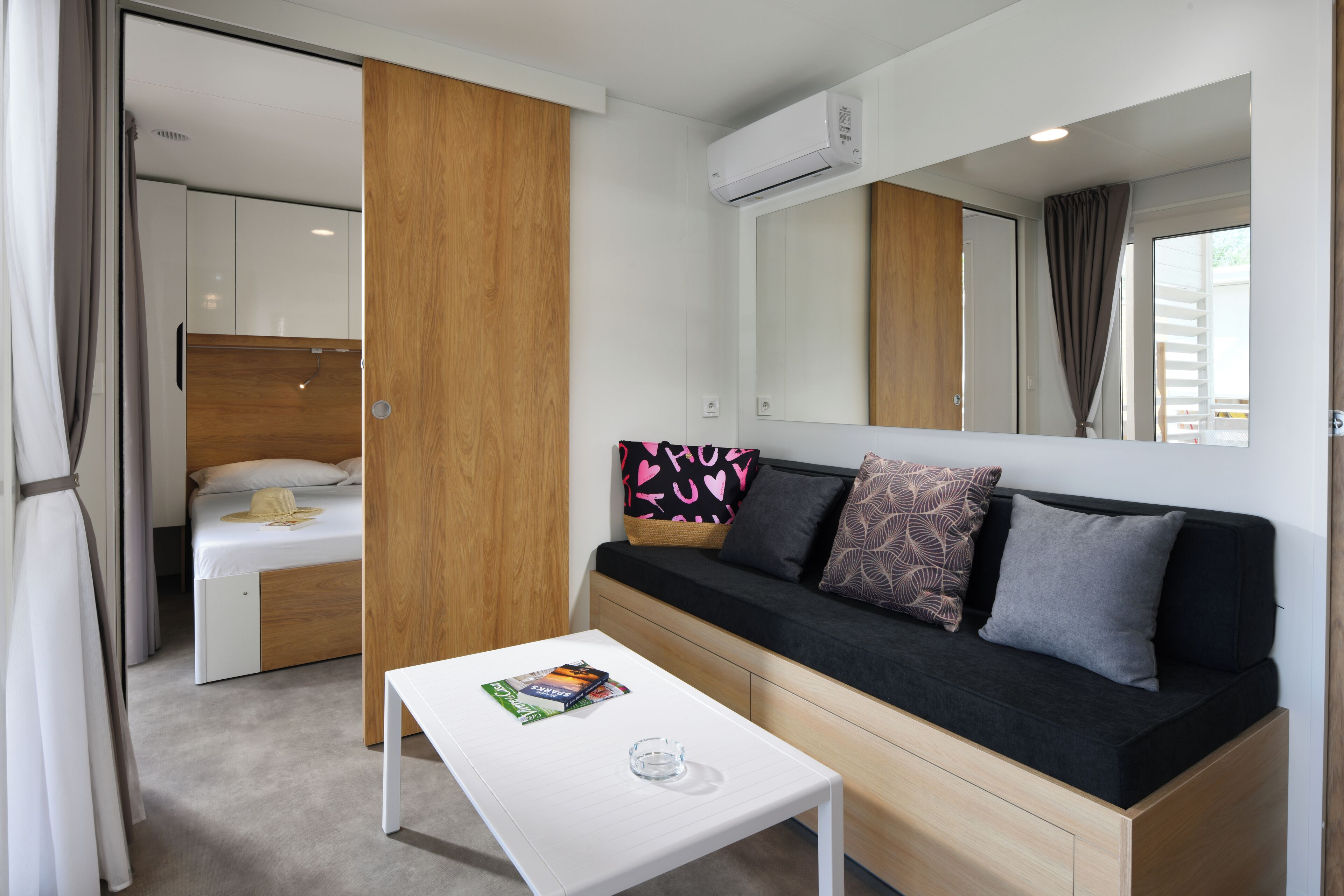 Een moderne hotelkamer met een bed, een bank, een bijzettafeltje en een grote spiegel.