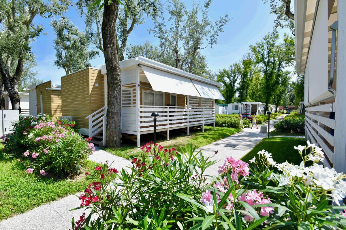 A row of mobile homes with a paved walkway and flower beds in front.