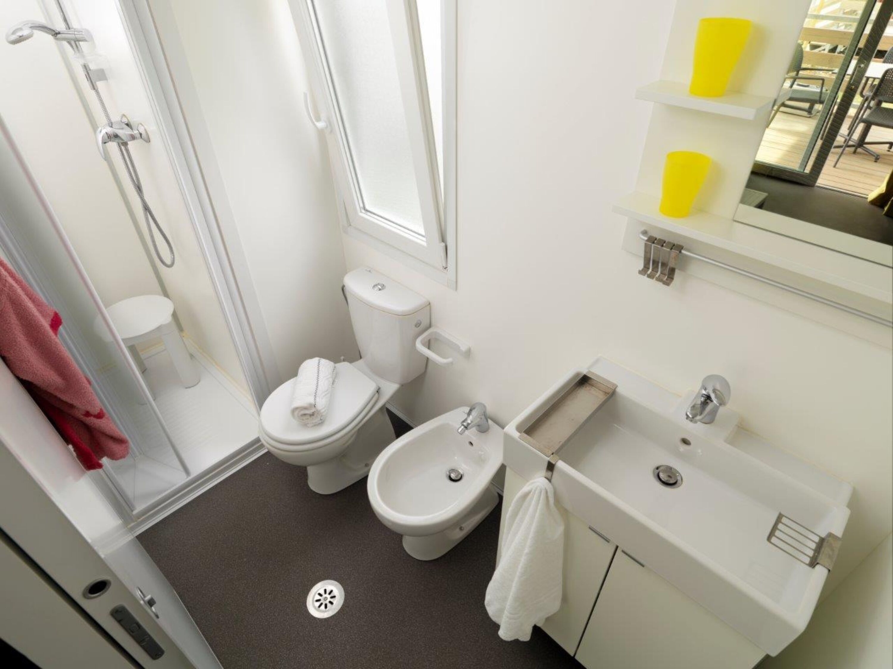 A compact bathroom with a shower, toilet, bidet, and sink.
