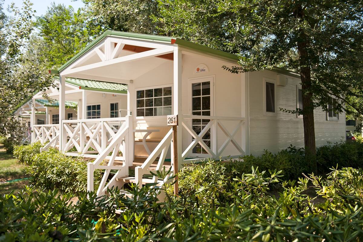 A white building with a green roof, a porch, and a number 261 sign.