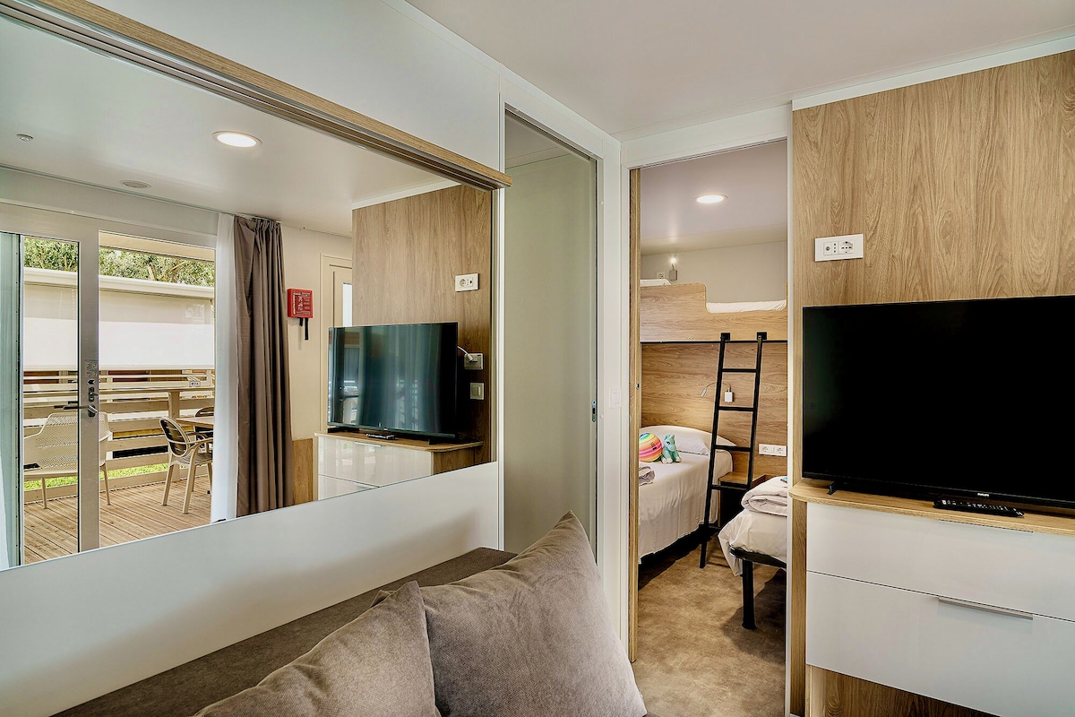 Une chambre de taille modeste comprenant un lit, un téléviseur et un coin salon avec une table et des chaises.