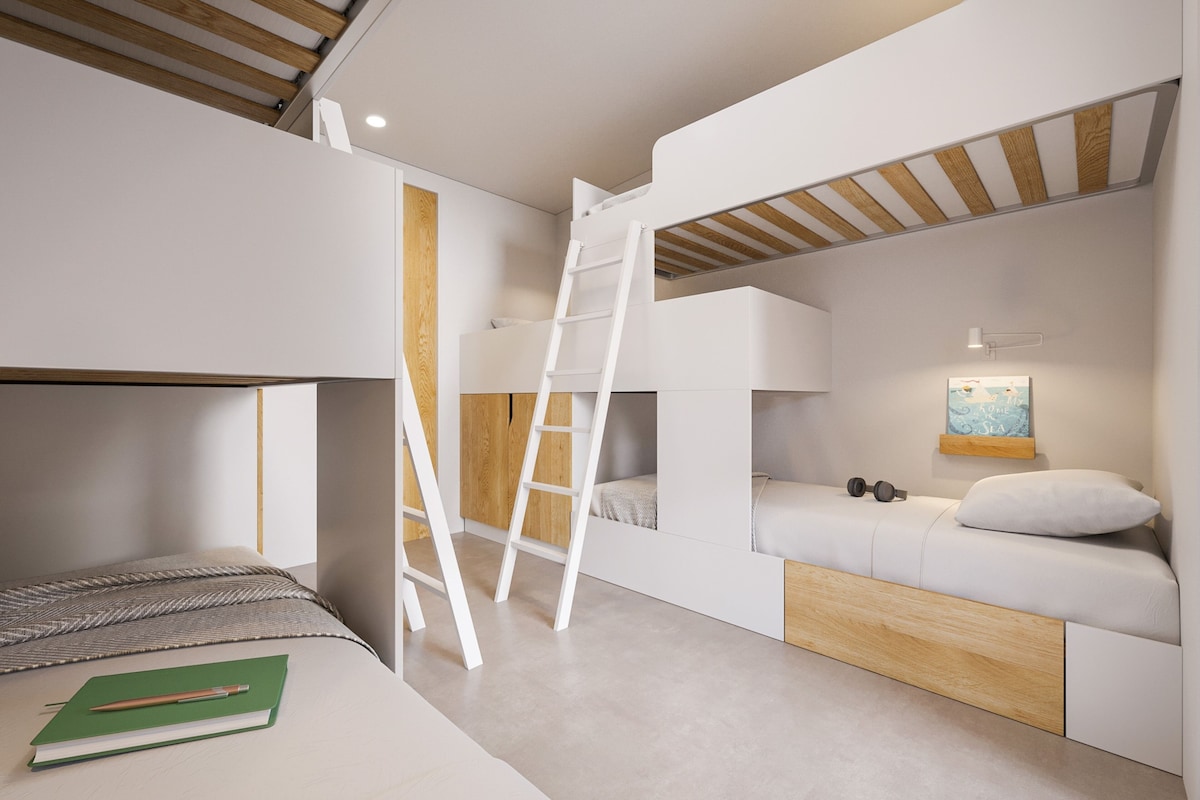 Une chambre avec un lit superposé, une échelle, un bureau avec un carnet et une étagère murale avec un tableau.