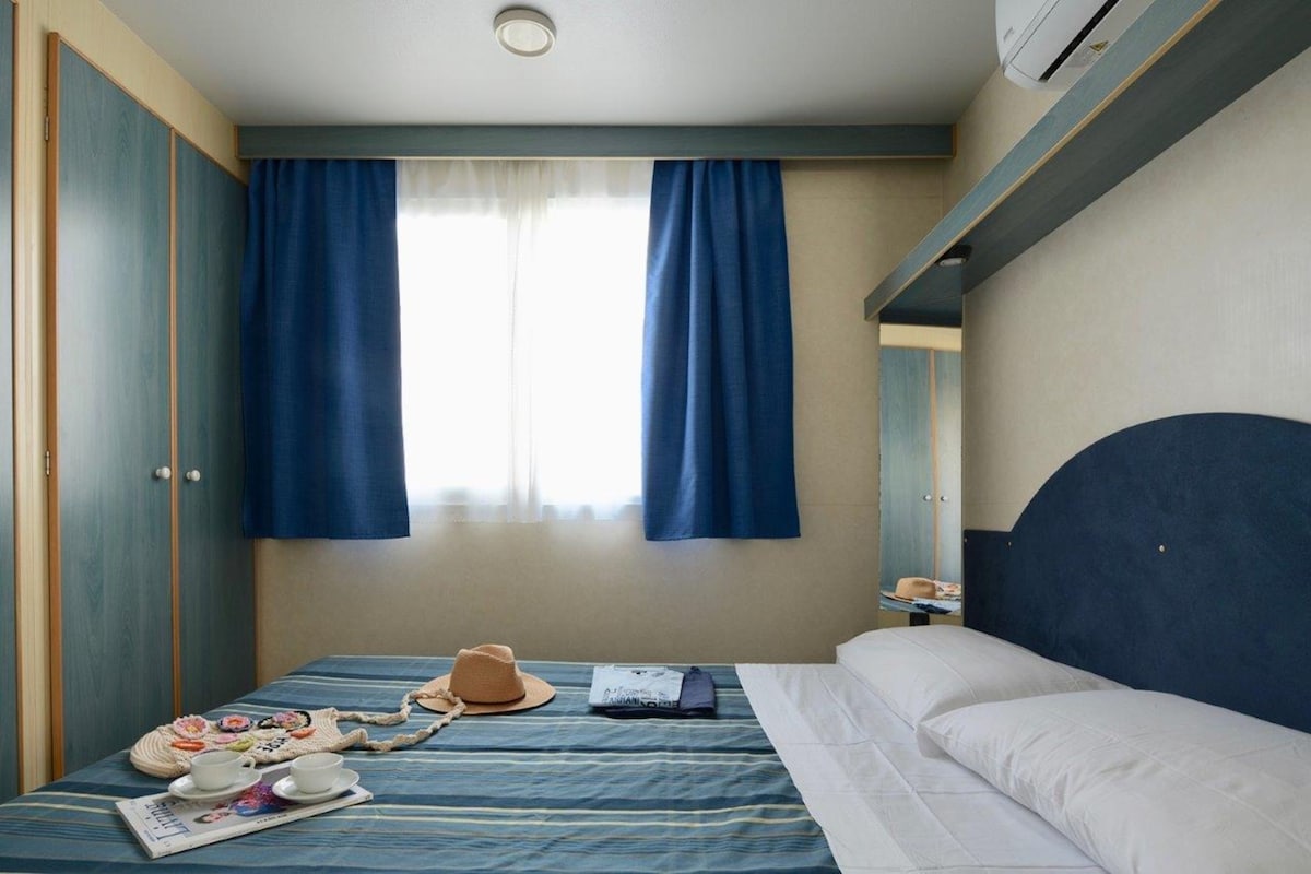 Une chambre d’hôtel avec un lit, une fenêtre avec des rideaux, une table de chevet et une armoire.