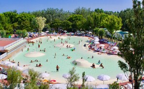 A large outdoor swimming pool with multiple lanes, surrounded by beach chairs and umbrellas. - Isamar Holiday Village (Chioggia)