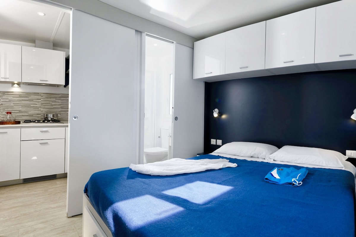 Une chambre d’hôtel moderne dotée d’un grand lit, d’une salle de bain séparée et d’une kitchenette.