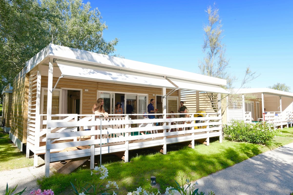 A row of mobile homes with white railings and a covered porch area.