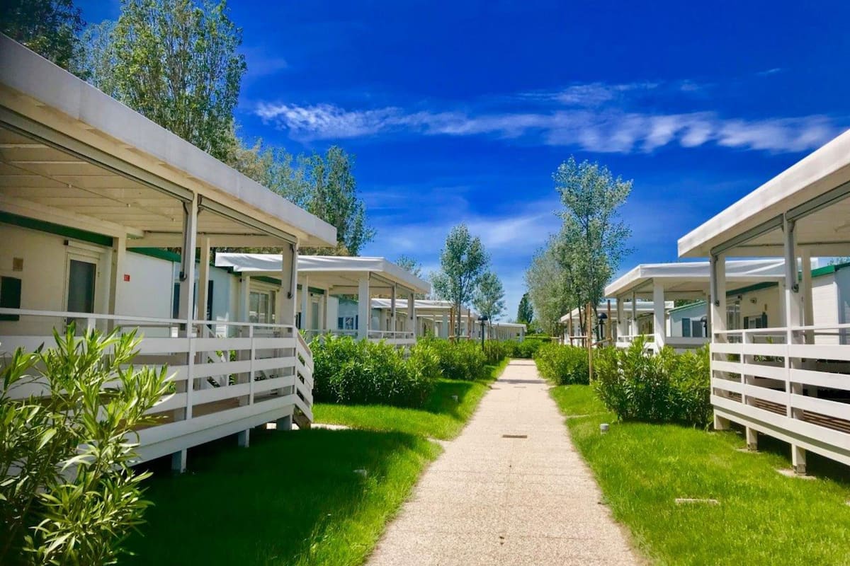A row of single-story cabins with a gravel path leading through a green landscape.