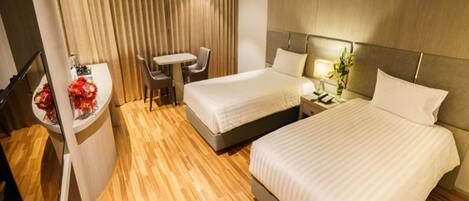 Quarto de hotel com duas camas, uma escrivaninha e uma cadeira.