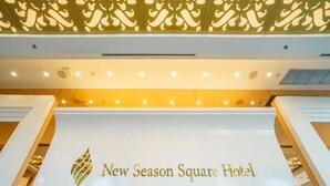 Exterior do Hotel New Season Square com uma placa em destaque exibindo o nome do hotel e um logotipo decorativo.