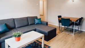 Una sala de estar moderna con un sofá seccional gris, una mesa de centro blanca y una mesa de comedor con sillas.