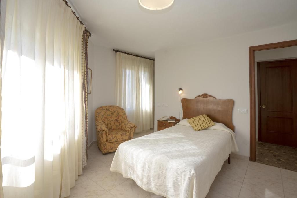 Une chambre à coucher avec un lit, une chaise, une table de chevet et une porte.