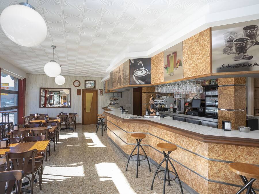 A café with a counter, stools, and tables.