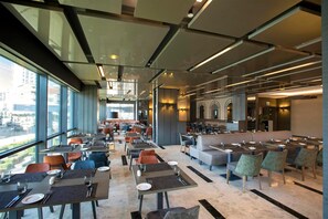 A modern restaurant with high ceilings, large windows, and a mix of seating arrangements including tables and booths. - Wish More Hotel Istanbul (Istanbul)