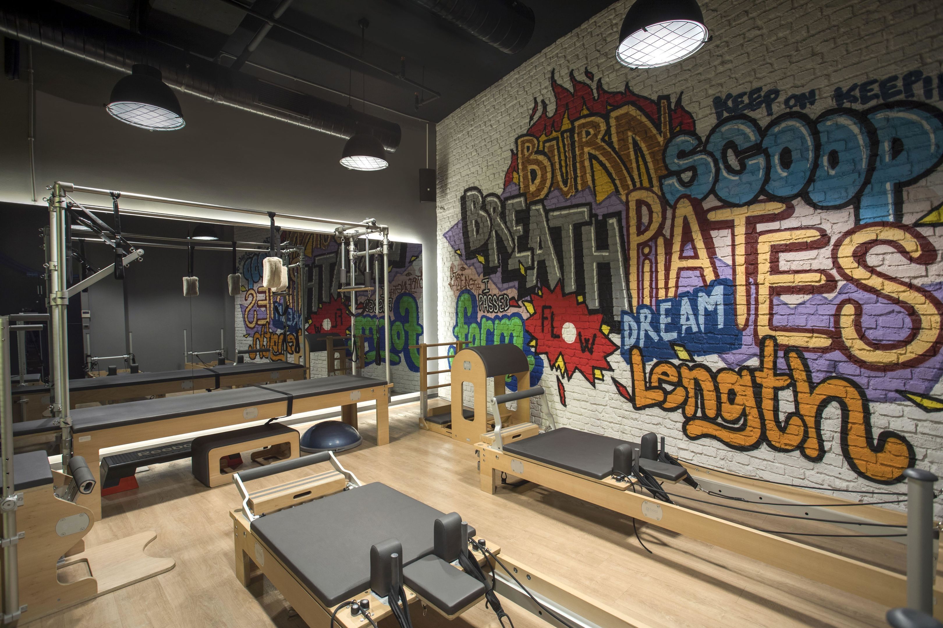Un gimnasio con equipamiento de ejercicio y una pared con grafitis y frases motivadoras.