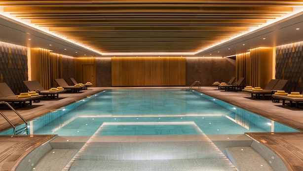 A modern indoor swimming pool with a long, rectangular shape, surrounded by lounge areas with seating and towels. - Wish More Hotel Istanbul (Istanbul)