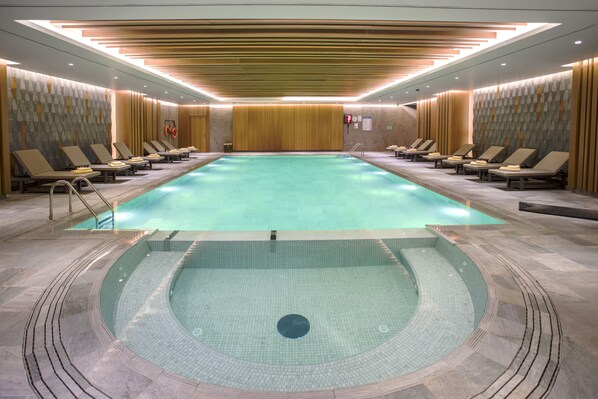 A large indoor swimming pool with lounge chairs and a separate hot tub area. - Wish More Hotel Istanbul (Istanbul)
