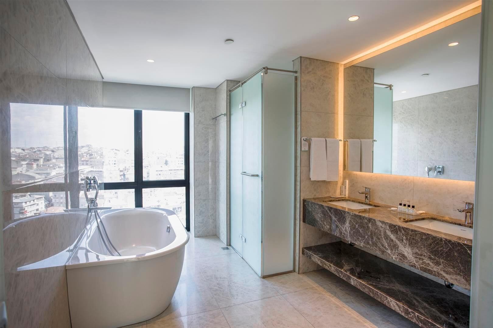 A modern bathroom with a freestanding bathtub, a large mirror, and a vanity with a marble countertop.
