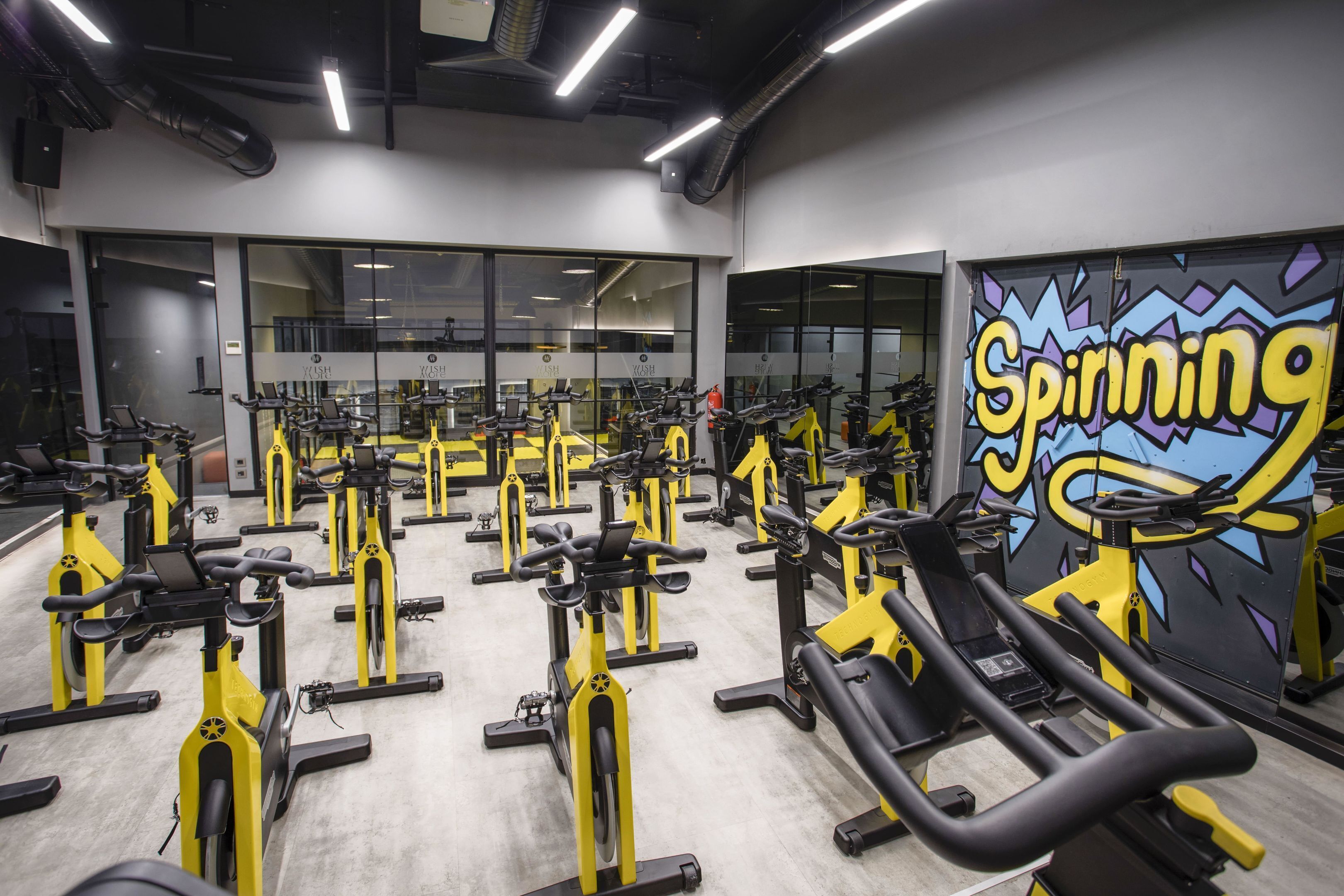 A gym with multiple stationary bikes and a large mural with the word "Spinning".