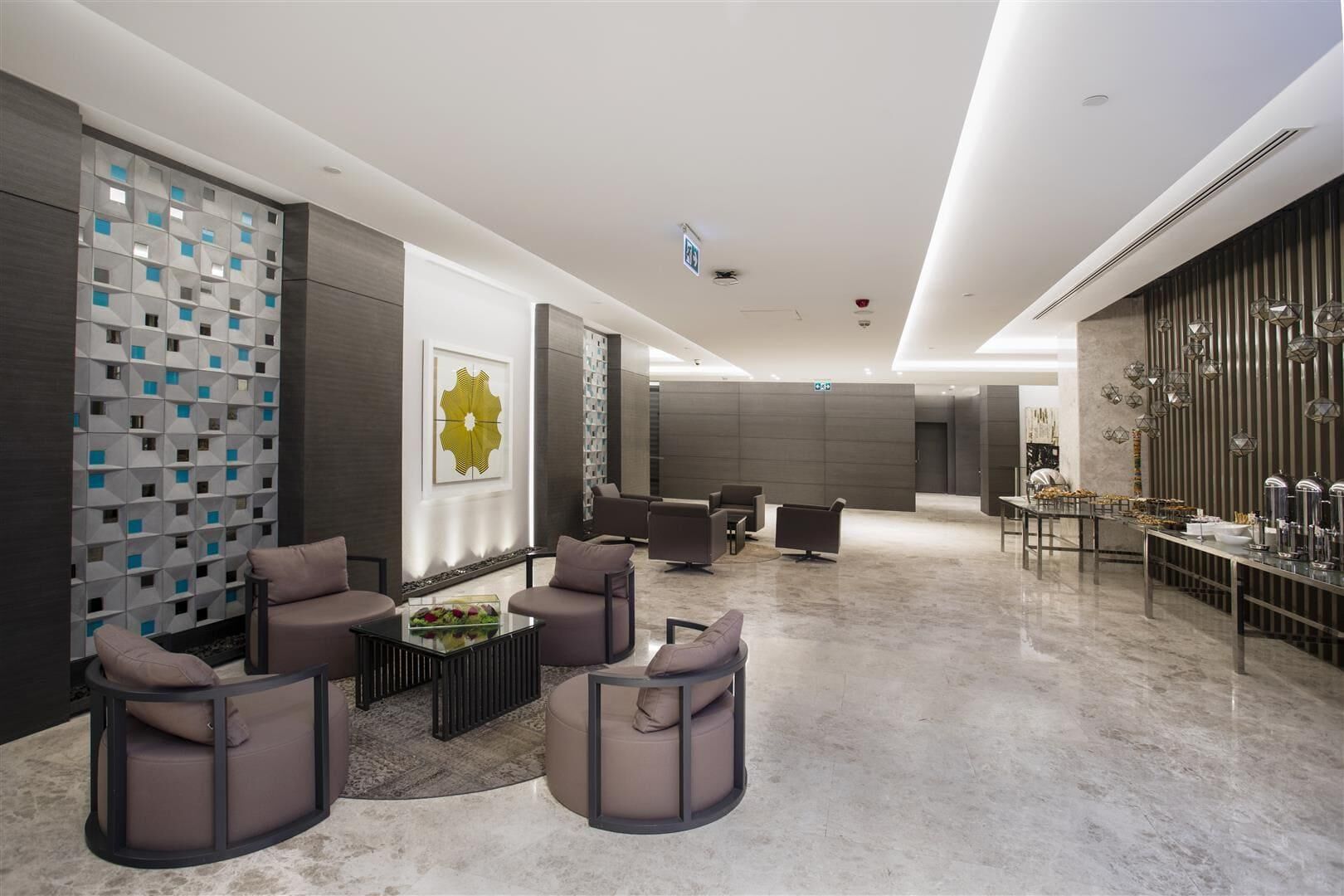 A modern lobby with a seating area, a buffet, and a decorative wall with geometric patterns.