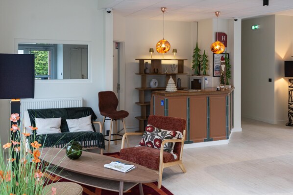 Un moderno vestíbulo de hotel con un sofá, un sillón y una recepción.