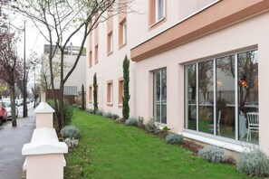 A modern building with large windows, a well-maintained lawn, and a pathway leading to the entrance. - Kyriad - Joinville-Le-Pont (Joinville-le-Pont)