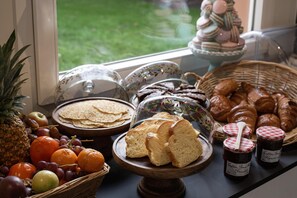 Un bufé de desayuno con pan, bollería y frutas.