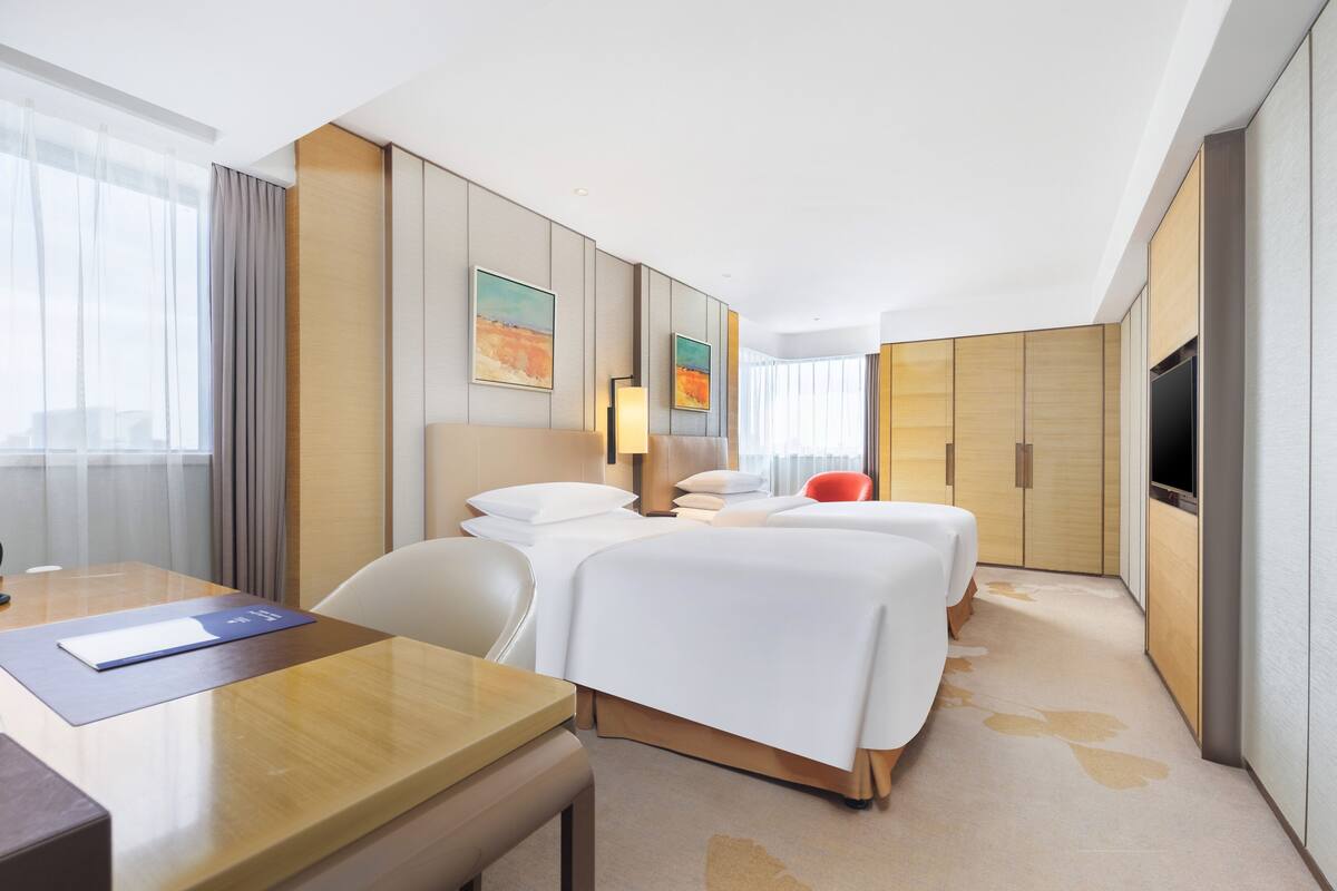 Ein Hotelzimmer mit Bett, Schreibtisch, Stuhl und Fernseher.