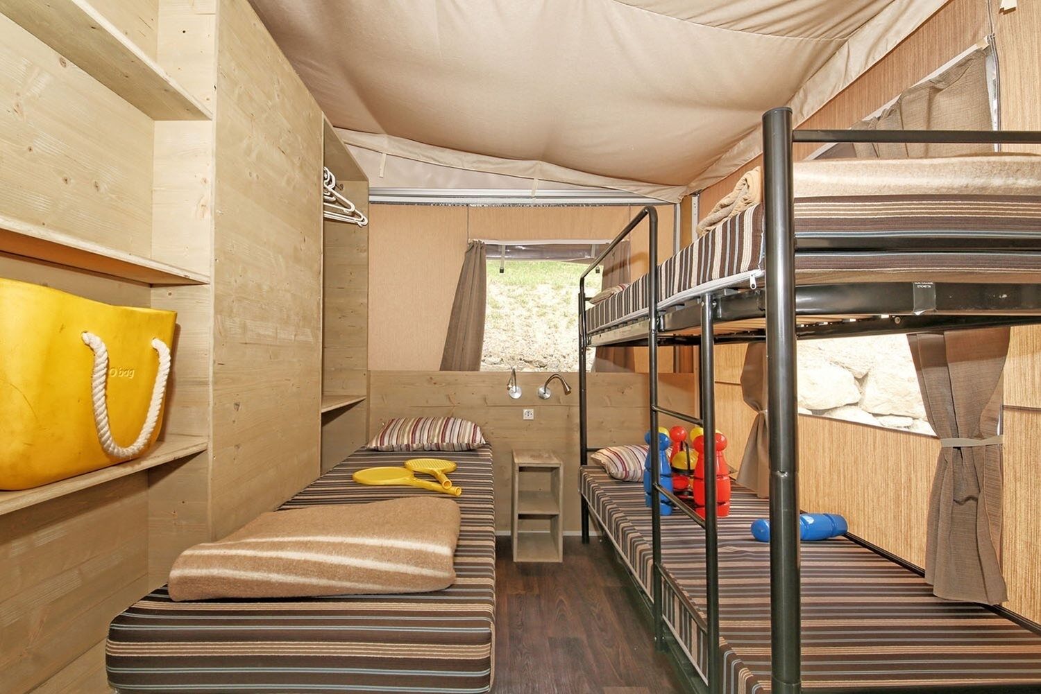 Un espacio para dormir compacto con literas y una pequeña zona de estar, con interior de madera y vistas al exterior.