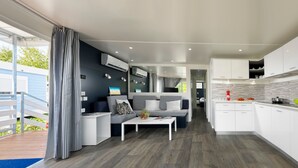 Ein kompakter Wohnraum mit Küchenzeile, Essbereich und einer Sitzecke mit Sofa und Couchtisch.