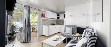 A modern kitchen with white cabinets, a striped sofa, and a dining area with a white table.