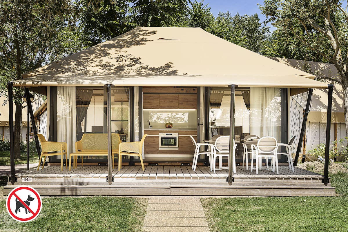 A covered outdoor seating area with a table and chairs, a bench, and a small table with a vase.