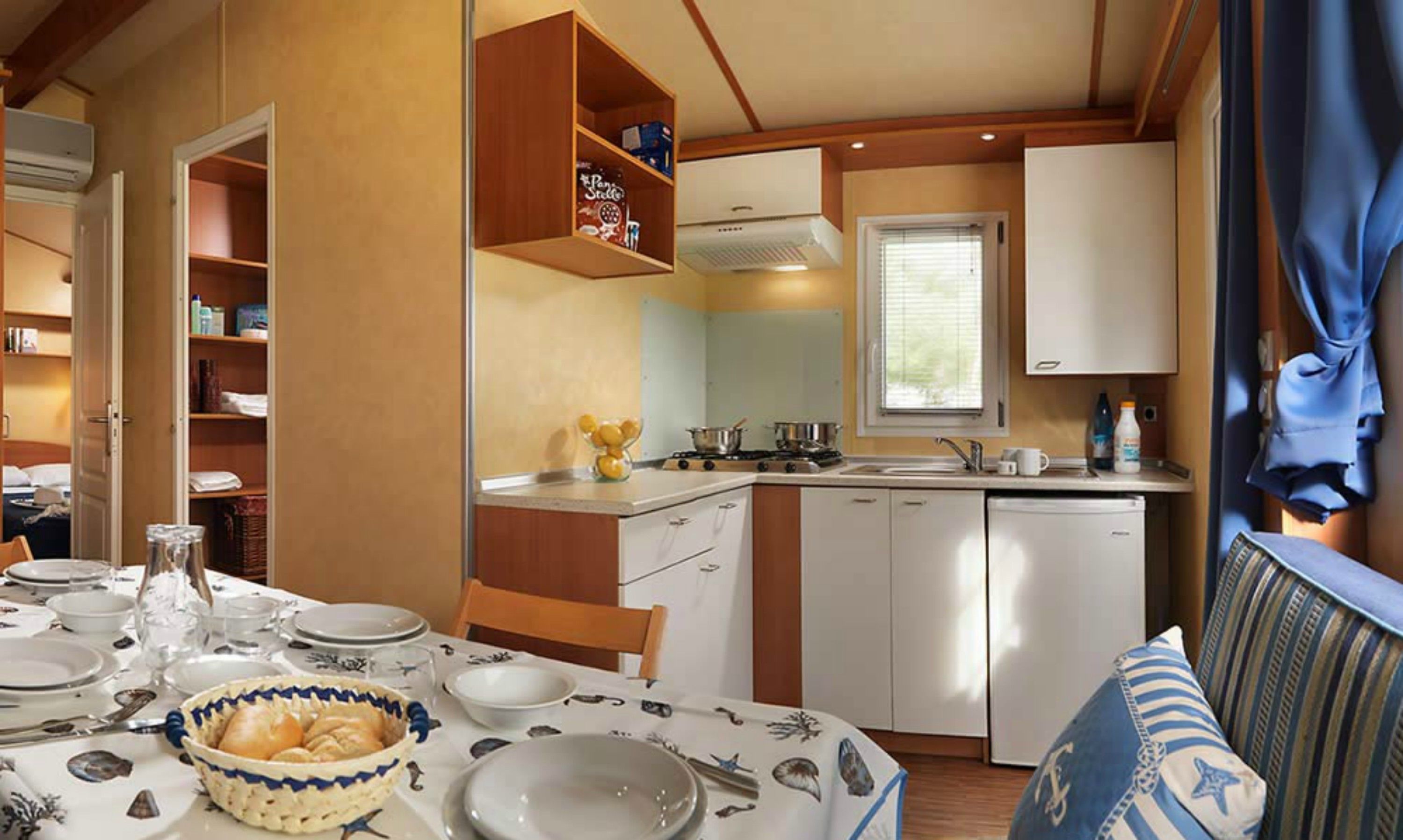 Una cocina compacta con comedor, que incluye una mesa dispuesta para comer, un fregadero y una estufa.