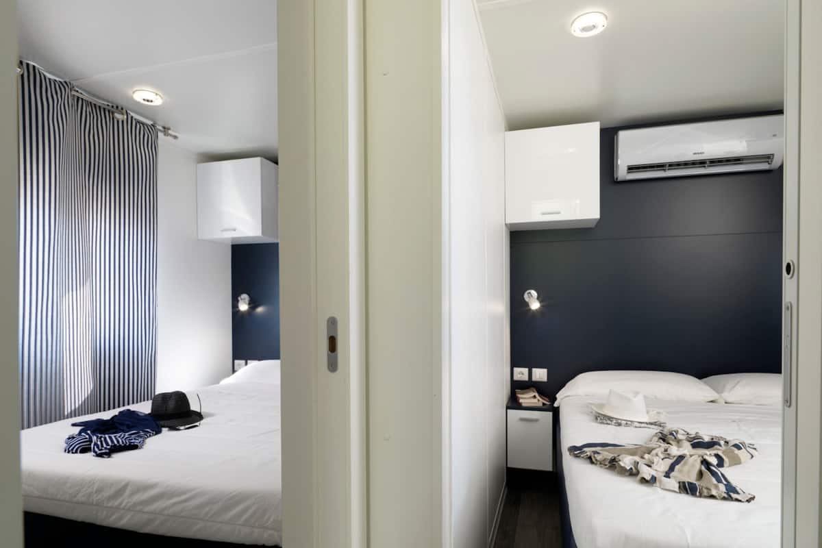 A modern hotel room with a bed, bedside table, and an air conditioning unit.