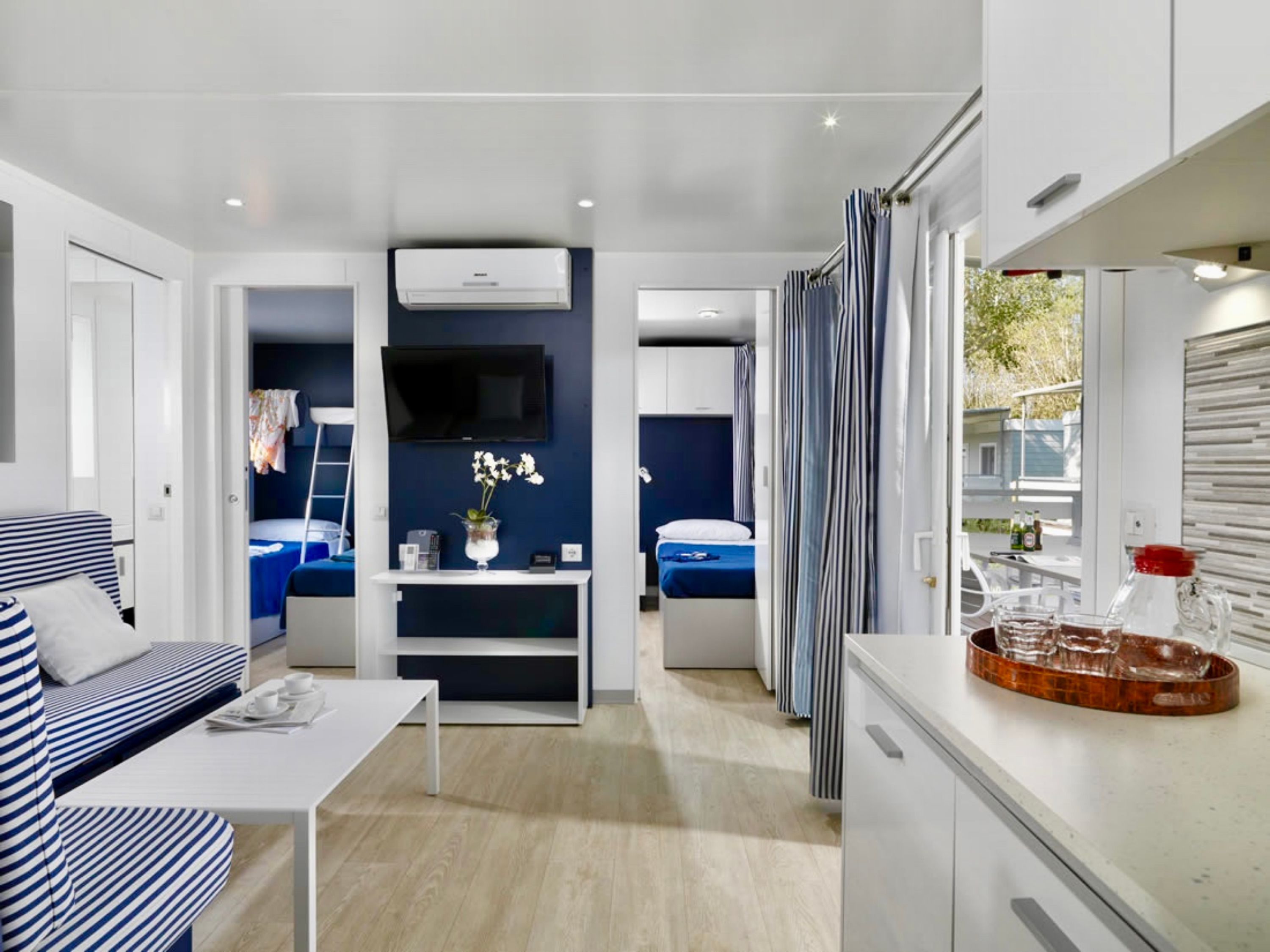 A modern, compact living space with a kitchenette, a dining area, and a bedroom.