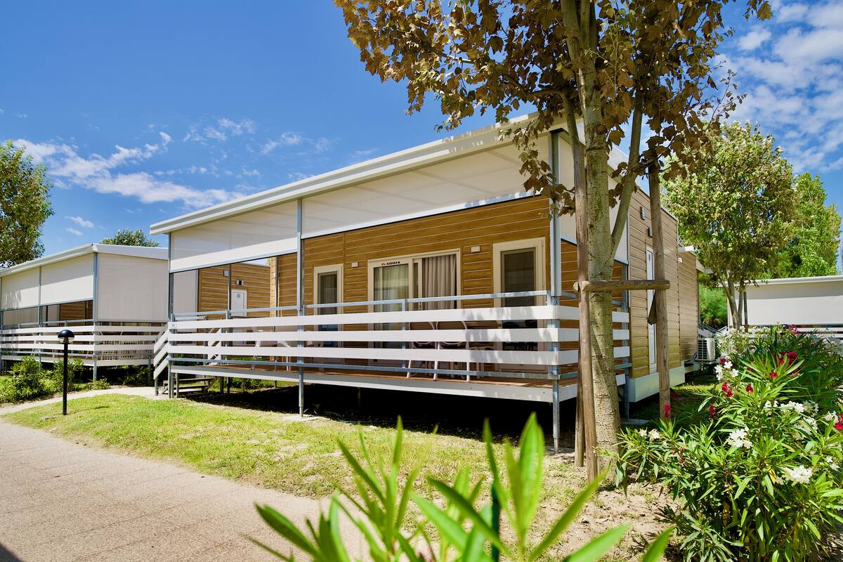 A modern RV-style building with a covered porch and a small garden area.
