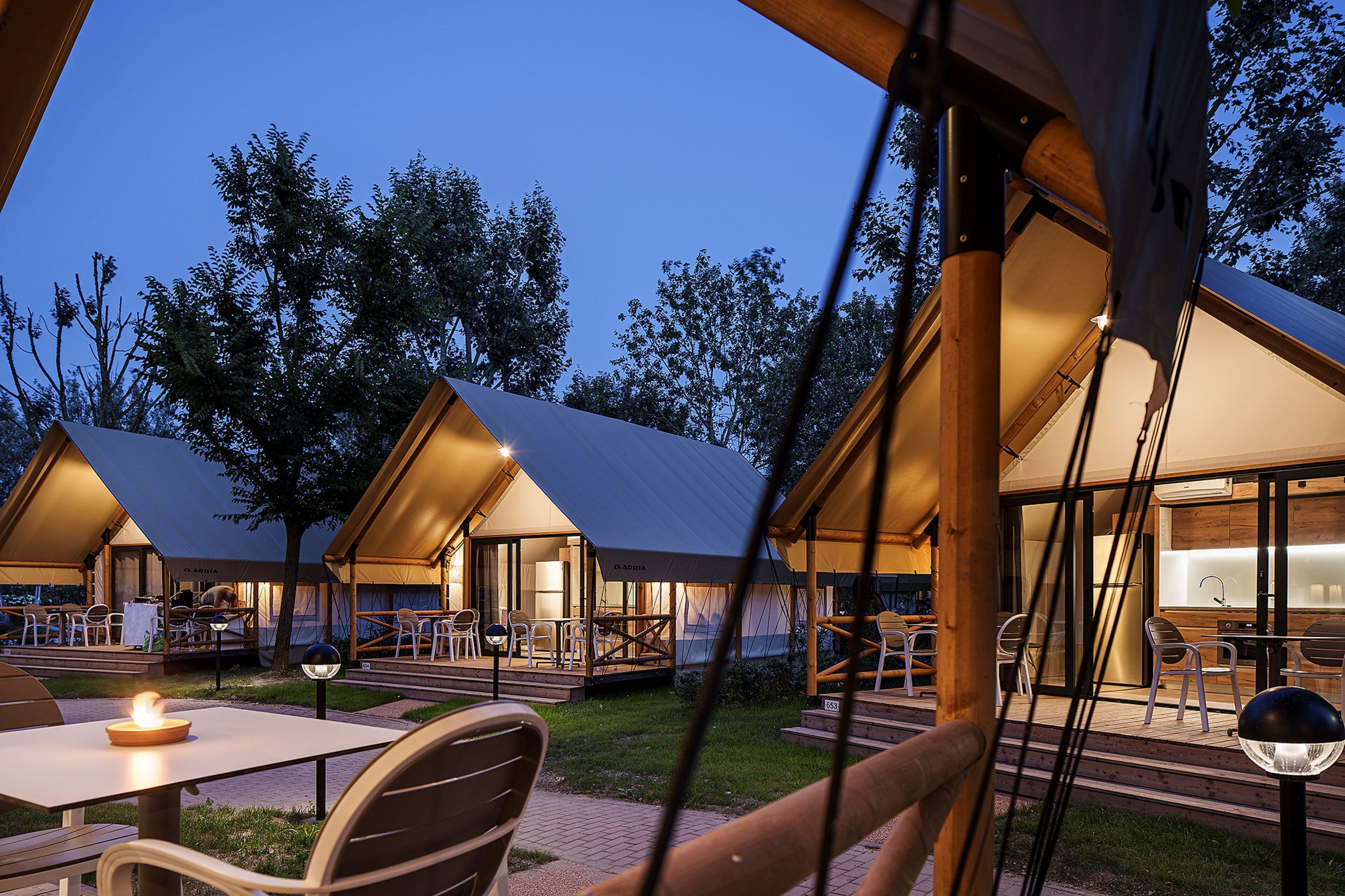 A series of modern, well-lit tents with outdoor seating areas and a visible kitchen area.