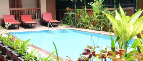 A pool area with lounge chairs and potted plants.