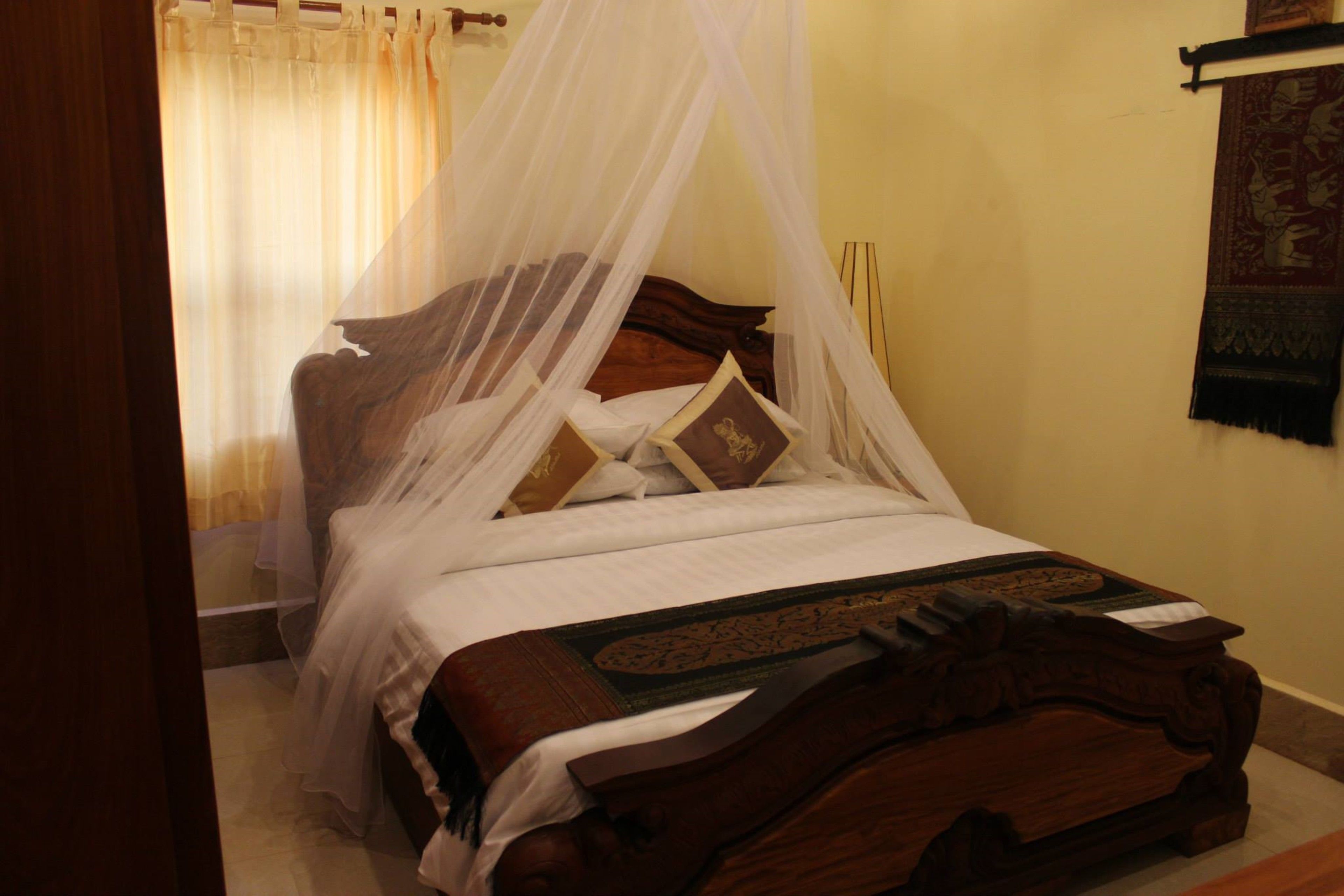 A bed with a canopy, pillows, and a blanket.