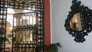 Una ornamentada puerta de hierro forjado con un arco rojo, un espejo decorativo en la pared y una vista de una habitación con una decoración roja y blanca.