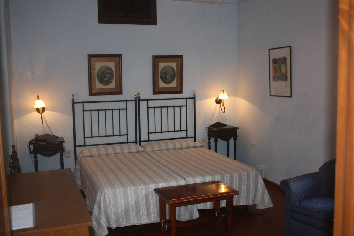 A hotel room with a double bed, two bedside tables, a desk, and a chair.