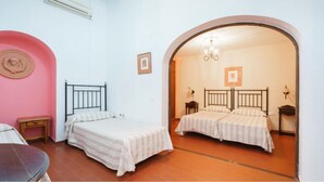 Un dormitorio con dos camas, una pared rosa y suelo de baldosas.