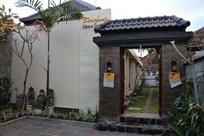 Una puerta tradicional con techo de tejas, que conduce a un edificio con un cartel que dice "Blanjong Home Stay".