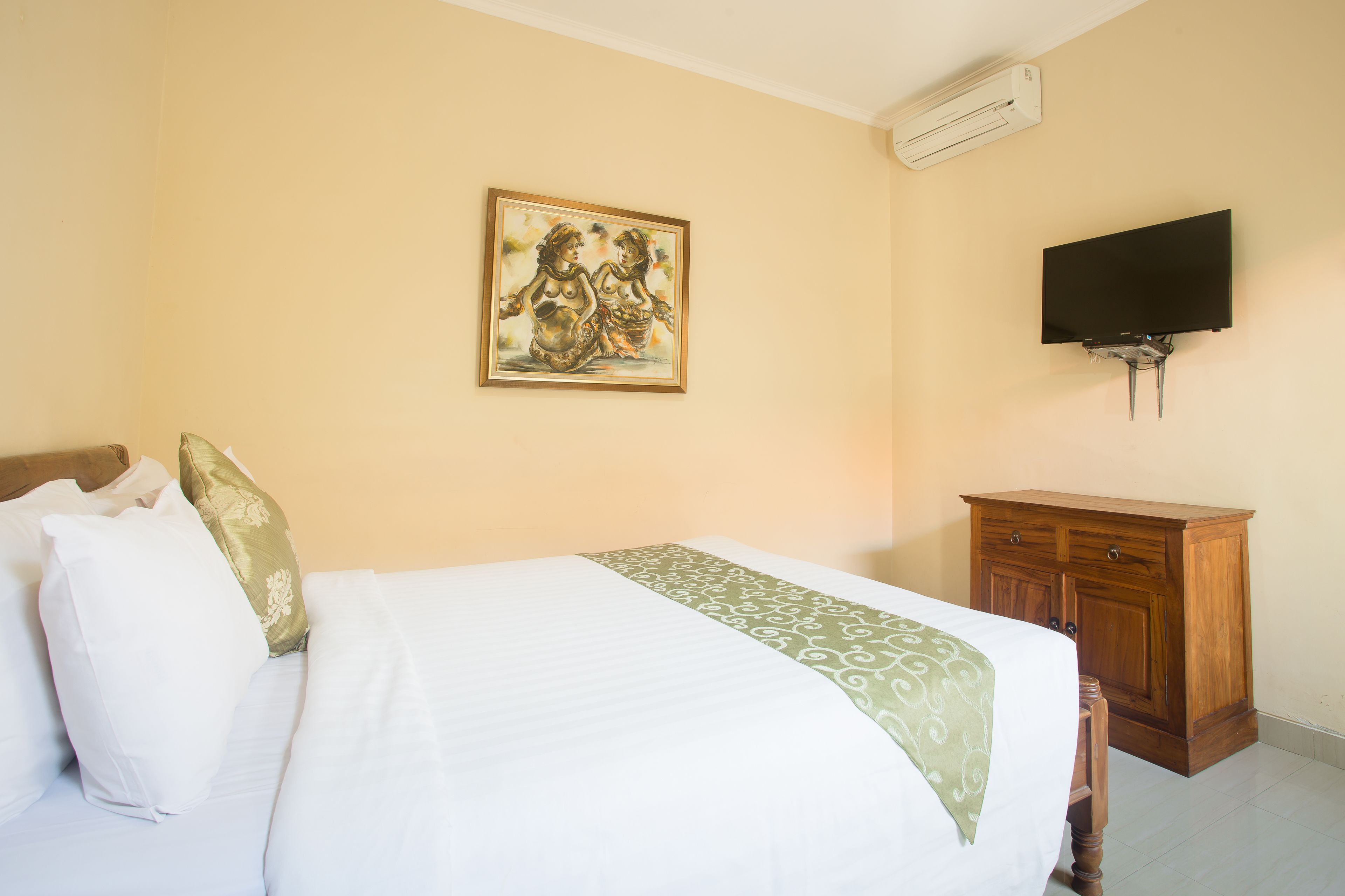 A bedroom with a bed, a painting, a TV, and a wooden cabinet.
