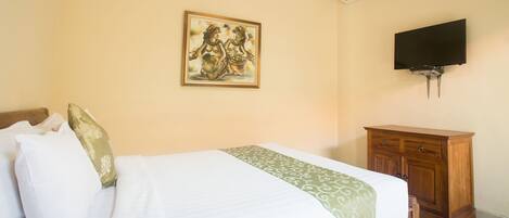 A bedroom with a bed, a painting, a TV, and a wooden cabinet.
